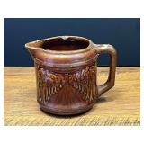 Garage… Vintage pitcher, believed to be vintage Brush-McCoy stoneware pitcher in the "Avenue of Trees" (or Woodland) pattern with a brown Rockingham glaze, see pictures for details.