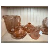 DR… Shelf lot of pink Depression glass in the “Cherry Blossom” pattern to include butter dish, serving bowl, plates, saucers, creamer and sugar, and more. See pictures for details.