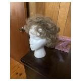 A wig with a head and a jar of fake flowers