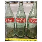 Three glass Coca Cola 32 oz bottles