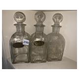 THREE DECANTERS W/ STOPPERS AND 2 ID