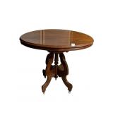 OVAL WOOD TABLE WITH CARVED BASE ON CASTERS 25"W