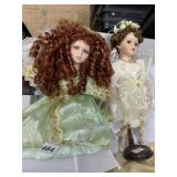 TWO PORCELAIN DOLLS ONE WITH WINGS AND GREEN