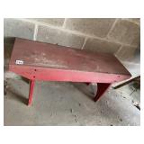 RED PAINTED WOODEN BENCH.