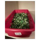 ASSORTED GREEN & CLEAR GLASS PEBBLES IN RED BIN.