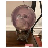 SKULL IN PURPLE GLASS SPHERE, METAL TRIPOD STAND.