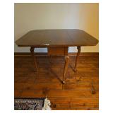 Drop-leaf table with cherry finish and turned legs. Features hinged leaves supported by swing-out gate legs, allowing the table to expand for use or fold down for compact storage. Traditional styling 