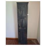 Tall standing cabinet with narrow profile and paneled door. Features wood construction with simple traditional styling. Measures approximately 78 in. tall x 18 in. wide x 13 in. deep.
