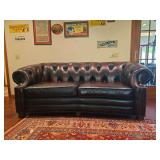 Seven Seas leather sofa with rolled arms, nailhead trim, and carved wood accents. Measures approximately 35 in. tall x 88 in. wide x 44 in. deep. Please review photos for condition, wear, and details.