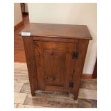 Small wooden storage cabinet with single door and interior shelf. Features natural wood construction with simple country or primitive styling. Measures approximately 31 in. tall x 23 in. wide x 13 in.