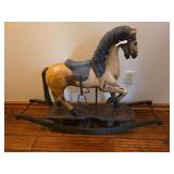 Antique wooden rocking horse with painted finish and traditional curved rocker base. Features carved horse form with age-related wear and primitive decorative character.