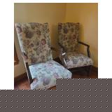 Pair of matching upholstered sitting chairs with exposed wood frames and carved details. Features upholstered seats and backs with traditional styling suitable for a sitting room, bedroom, or accent s