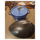 Two Staub enameled cast iron cookware pieces including a 6 qt. wide round shallow cocotte / Dutch oven and a Staub mussel pot. The wide shallow cocotte is designed with a broad cooking surface and low