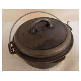 Vintage Wagner cast iron Dutch oven with fitted lid and wire bail handle. Appears to primarily need cleaning and reseasoning.