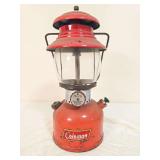Coleman Model 200A pressure lantern marked 6/59, with red painted fount, matching red porcelain ventilator, clear Coleman globe and wire bail handle. Shows paint wear, soiling and age-related use.