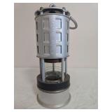 Koehler Mfg. Permissible Flame Safety Lamp No. 209 with silver-tone metal body, protective upper housing, glass chamber and carrying hook/handle. Shows surface wear, discoloration and age-related use.