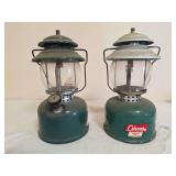 Pair of Coleman LP Gas Propane Lanterns. Two Coleman propane lanterns with green-and-metal finishes, clear globes and wire bail handles as shown; both show general age-related wear and surface soiling