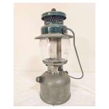 Coleman Model 242C pressure lantern marked 12/48, with silver-tone fount, green porcelain ventilator, clear Pyrex Coleman globe and wire bail handle. Shows age-related wear and oxidation.