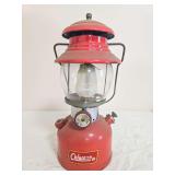 Coleman Model 200A pressure lantern with red fount and red porcelain ventilator, clear Coleman globe and wire bail handle; marked 8/61. Shows surface wear, dust and age-related use.