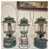 Coleman Models 5101, 220K & 220J Lanterns – Marked 10/80 & 6/75. Includes LP-gas Model 5101 and two green liquid-fuel lanterns with clear globes and wire bail handles; shows varying age-related wear