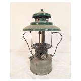 Coleman Model 220B pressure lantern marked C/38, with silver-tone fount, green porcelain ventilator, clear glass globe and wire bail handle. Shows oxidation and age-related surface wear.