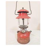 Coleman Model 200A pressure lantern marked 7/61, with red painted fount, matching red porcelain ventilator, clear Coleman globe and wire bail handle. Shows paint wear and age-related use.