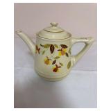 Hall Autumn Leaf teapot-form music box with floral decoration and gold trim. Fitted with an internal wind-up musical movement; handwritten label reads “Pour Tea to Play the Song ‘Autumn Leaves.’