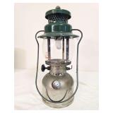 Coleman Model 242C pressure lantern marked 3/49, with silver-tone fount, green porcelain ventilator, clear Pyrex Coleman globe and wire bail handle. Shows age-related surface wear and oxidation.