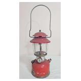 Vintage Coleman Model 200A pressure lantern with red painted fount, matching red ventilator, clear Coleman Pyrex globe and black wire bail handle; marked 9/64. Shows paint loss, oxidation and general 