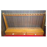 Large custom wooden long-gun rack with multiple barrel and buttstock positions and three lower storage drawers. Features decorative drawer pulls and natural stained finish.