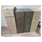 Four metal vertical filing cabinets in assorted gray and beige finishes, each with multiple drawers and label holders. Shows scratches, finish wear and general office use.