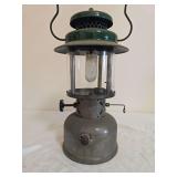 Coleman Model 237 Kerosene Lantern. Green painted fount with matching green porcelain ventilator, clear globe and wire bail handle; shows age-related finish wear, oxidation and surface soiling.
