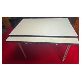 Metal-top utility table with light-colored rectangular top, black edge trim and tubular metal legs. Includes lower pull-out/extension surface as shown.