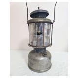 Coleman Quick-Lite pressure lantern with silver-tone fount, mica globe assembly and wire bail handle; cataloged as “66 w 35 on bottom.” Mica panels show damage and deterioration, with oxidation an