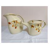 Two Hall China Autumn Leaf covered serving pieces with ivory glaze, floral decoration and gold trim, including a low rounded teapot with gold ball finial and a taller coffee pot. Teapot marked “Made