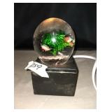 Glass ball with fish decor on black base that
