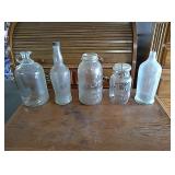 5 old glass jars and bottles two with lids.