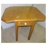 Oak drop leaf end table with decorative drawer.