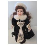 Porcelain doll on stand. Measures 17" tall.