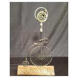 Vintage metal bicycle clock ornament on a carved
