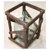 Large glass bottle in wooden crate