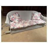 White wicker porch swing, cushions, pillows