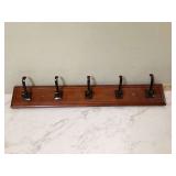 A wall-mounted rack for coats and hats with five hooks