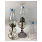 Clear glass oil lamps with chimneys.