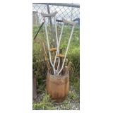 Barrel of tools: handsaws, shovel, hoe, hedge