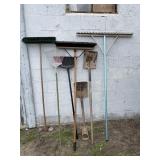 Lots of yard tools including brooms and water