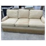 Cream color upholstered sofa with bullion fringe