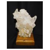 Milky quartz crystal cluster on wooden base,