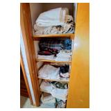 Hallway closet with blankets, sheets, table