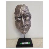 Silver-toned abstract sculpture of human face